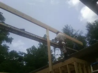 Carpenter setting a ridge beam over a new addition frame — Ice Dam Removal by Roofing Brothers in Carbon Cliff