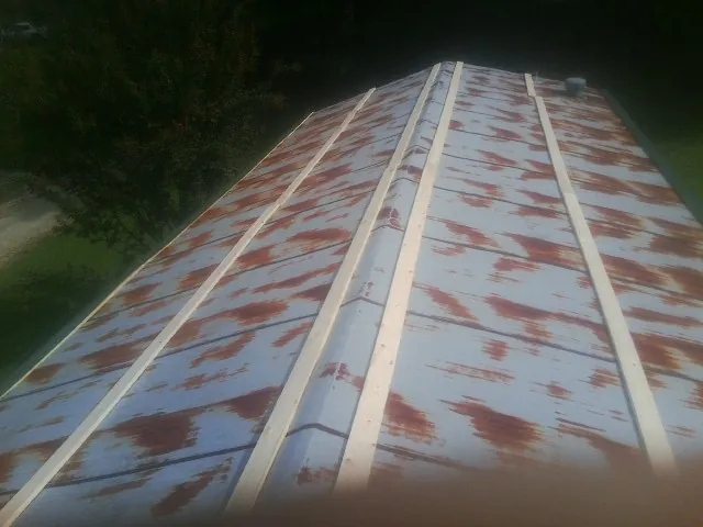Rusted metal roof panels with new wood purlins before replacement — Storm Damage Roof Repair in Carbon Cliff by Roofing Brothers