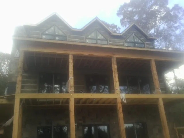 Dormers and porch framing on a large log home under construction — Roof Coating work by our crew in Carbon Cliff
