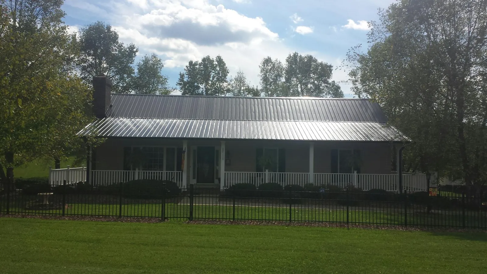 Gray metal roof on a brick ranch with a full width front porch — Gutter Guard Installation work by our crew in Carbon Cliff