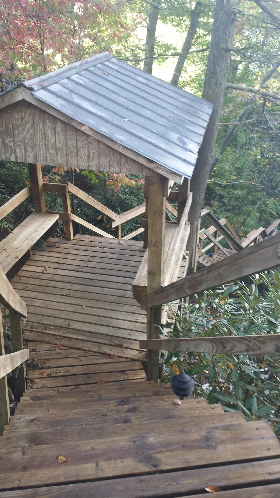 Metal roofed shelter over wooden steps on a wooded walkway — Skylight Repair & Installation work by our crew in Carbon Cliff