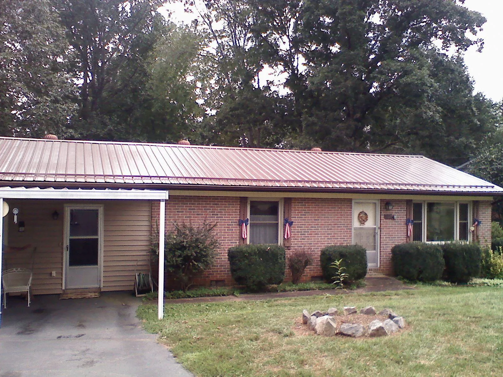 Bronze metal roof and carport on a brick ranch home — Roof Repair work by our crew in Carbon Cliff
